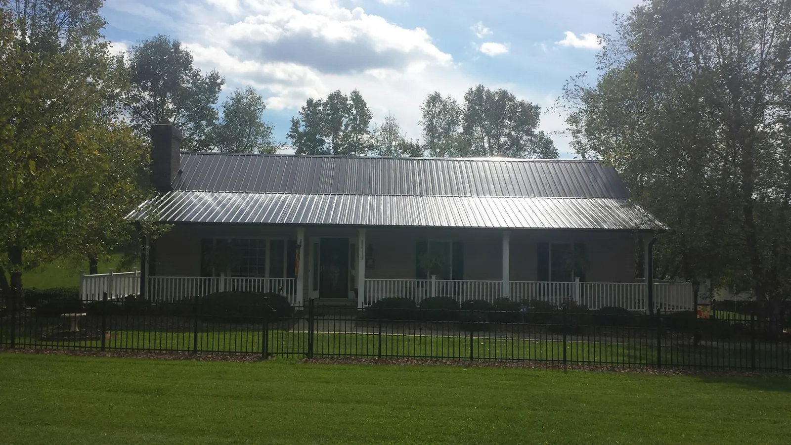 Gray metal roof on a brick ranch with a full width front porch — Gutter Guard Installation work by our crew in Yankton