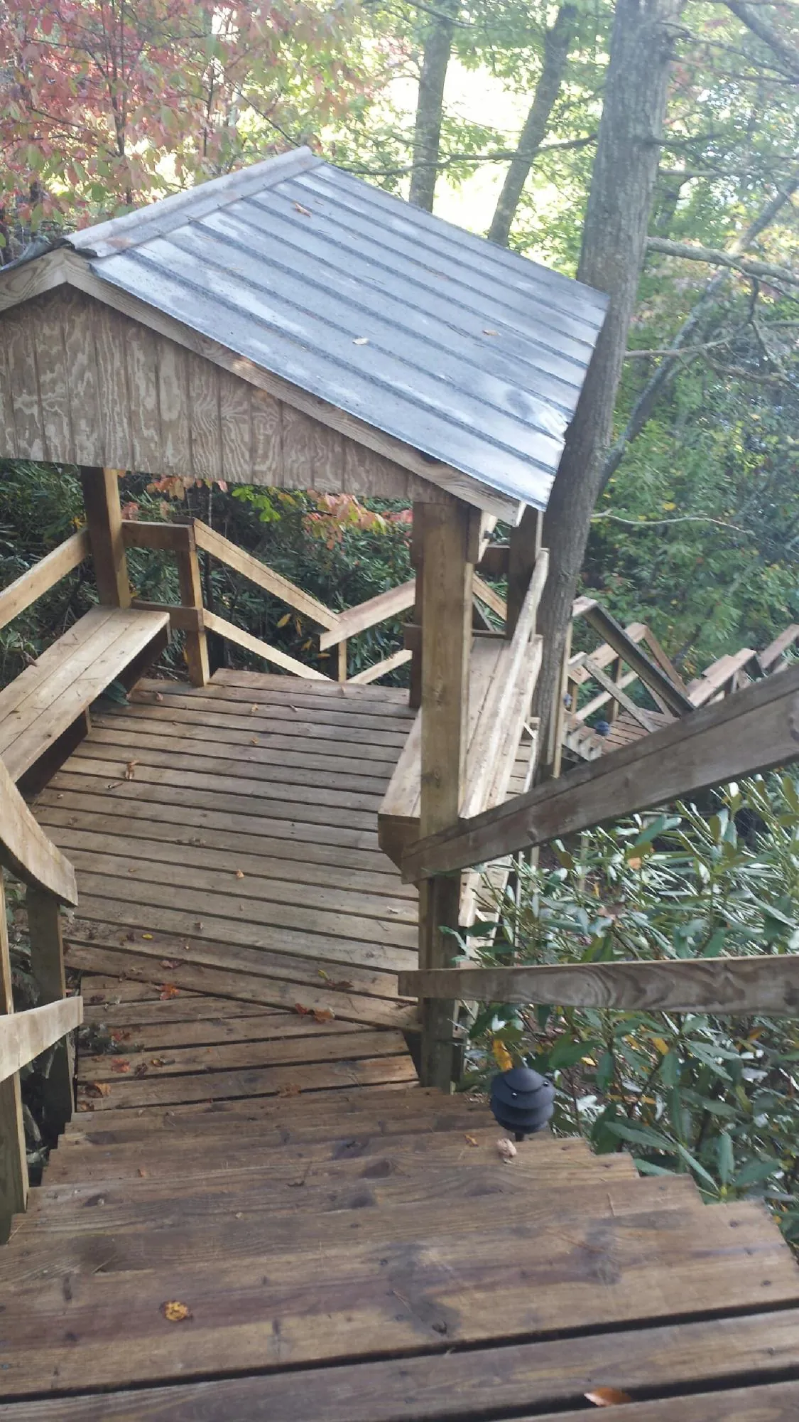 Metal roofed shelter over wooden steps on a wooded walkway — Skylight Repair & Installation work by our crew in Yankton